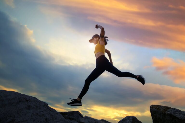 woman runs and jumping on mountain ridge at sunset